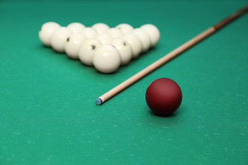 Different billiard balls and cue on table