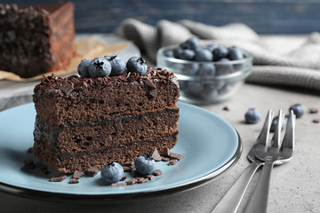 Delicious fresh chocolate cake served with blueberries on grey table