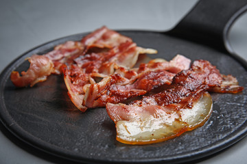 Slices of tasty fried bacon on grey table, closeup