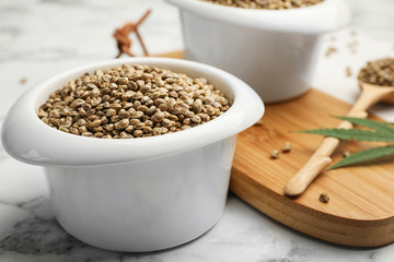 Organic hemp seeds in bowl on marble table