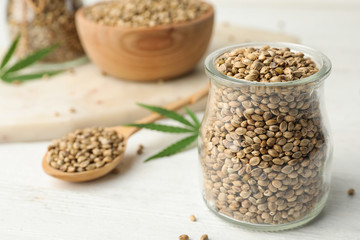Organic hemp seeds and leaf on white table