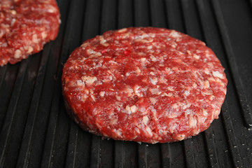 Raw meat cutlets for burger on grill, closeup