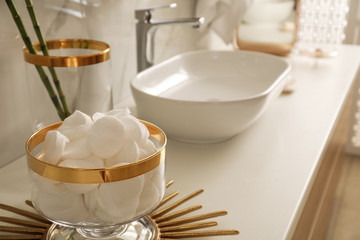Decorative jar with cotton pads on modern countertop in bathroom interior