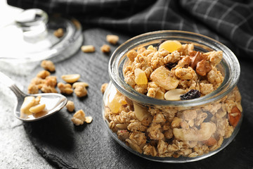 Jar of tasty homemade granola on grey table. Healthy breakfast