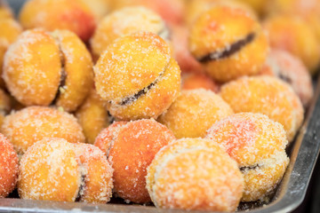 Large portion of freshly cooked peach cakes in display on a table at a street food market, side view