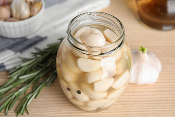 Composition with jar of pickled garlic on wooden table