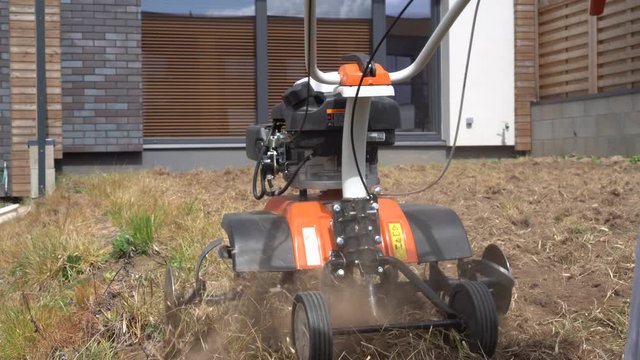 Man plow townhouse yard with cultivator. Preparing for lawn sow. Gimbal movement