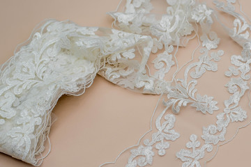 Texture lace fabric. lace on white background studio. thin fabric made of yarn or thread. a background image of ivory-colored lace cloth. White lace on beige background.
