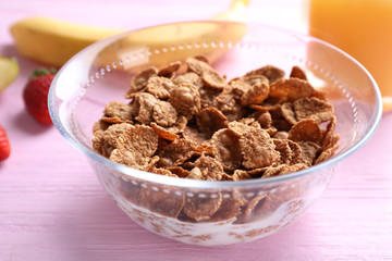 Cornflakes on pink wooden table, closeup. Healthy breakfast