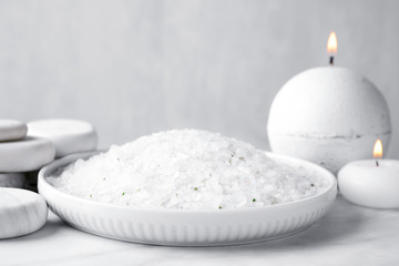 Fototapeta na wymiar White sea salt for spa scrubbing procedure on marble table against grey background