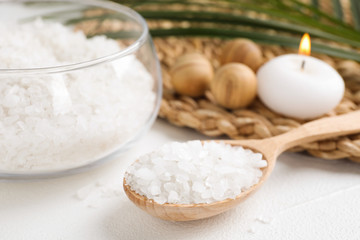 Wooden spoon with sea salt for spa scrubbing procedure on white table, closeup