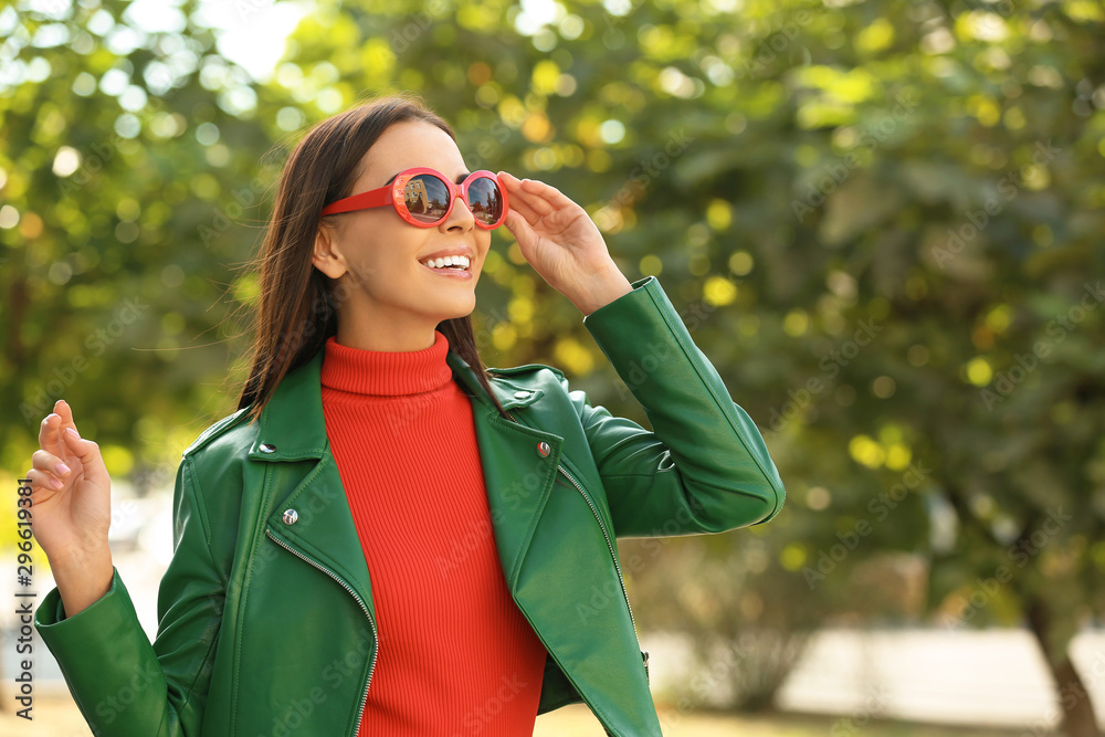 Wall mural beautiful woman wearing red sunglasses in green park