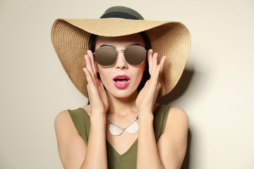Fototapeta premium Emotional woman in stylish sunglasses and hat on beige background