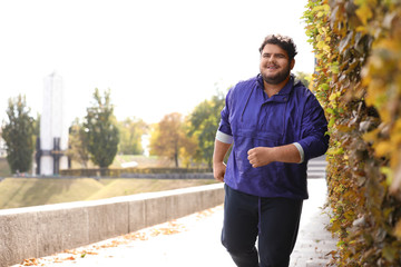 Young overweight man running in park. Fitness lifestyle