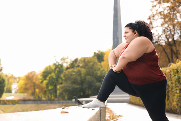 Beautiful overweight woman doing sport exercises in park