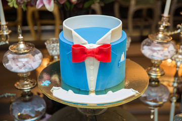 The concept of the desserts for the birthday boy . Beautiful blue cake for men, decorated in the form of a suit with a bow tie.
