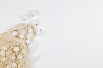 Xmas holiday decorative gray toys in eco-friendly shopping mesh bag on white background with copy space.