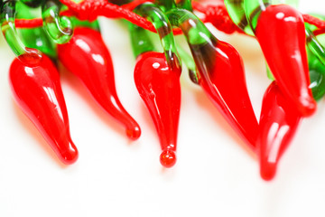 Red glass decorative peppers on white background with copy space. - Image