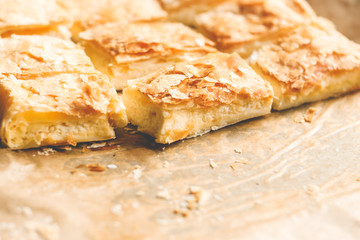 Crispy pie with cheese on the parchment paper background. Dish concept.