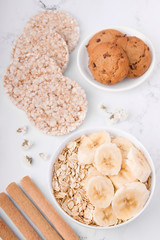 Breakfast of crispy bread cookies, oatmeal with banana on a light background