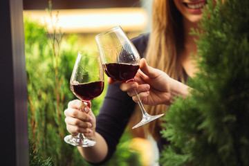 People clinking glasses with wine on the summer terrace of cafe or restaurant. Happy cheerful friends celebrate summer or autumn fest. Close up shot of human hands, lifestyle.
