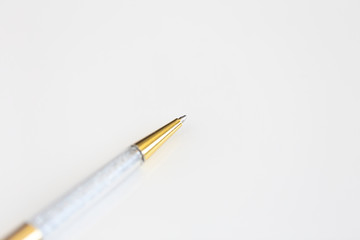 Macro photo of gold and crystal pen on white background