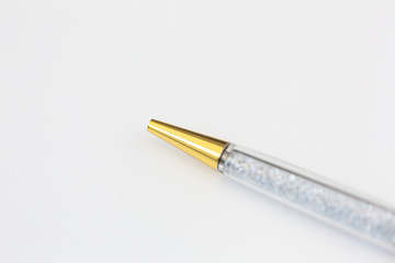 Macro photo of gold and crystal pen on white background