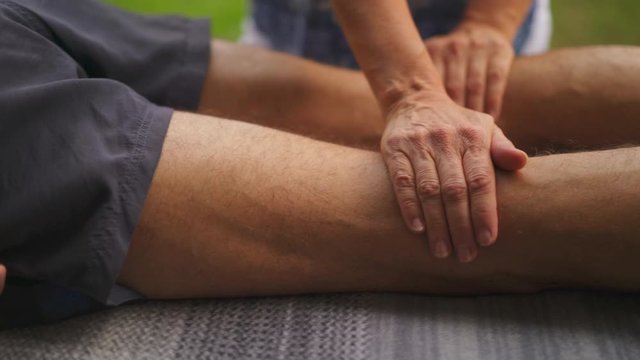 Man is lying on the belly and getting japanese reiki medical massage from professional therapist. Close Up Shot from the legs.