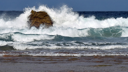 Powerful waves crashing on a large rock in sea. Taken at Sango Sands, Durness in the summer. Part of the North Coast 500 tourist route.