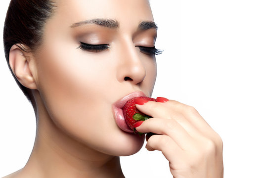 Serene beauty with red manicure relishing healthy fresh strawberry