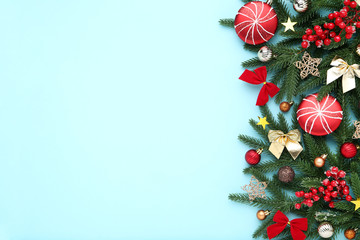 Christmas tree branches with toys and red berries on blue background