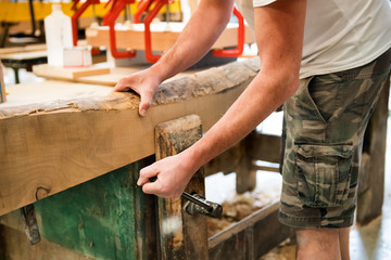 Carpenter tightening a wooden plank in a vice