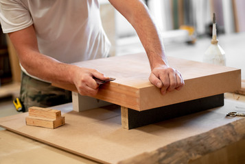 Carpenter sanding the edge of a wooden block