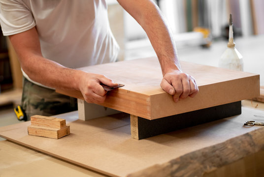 Carpenter sanding the edge of a wooden block