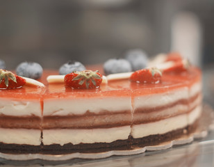 Selective focus on delicious chocolate and cream cake with strawberry and blueberry on the top. Shallow DOF. Tasty cake in a cake shop.
