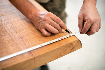 Fototapeta na wymiar Carpenter measuring a wooden plank