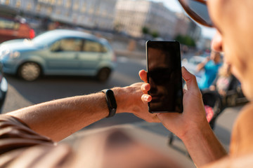 guy is looking at smart watch and smartphone. hands in the frame view from behind the shoulder.