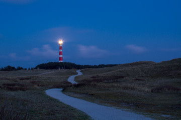 Path leading through the dunes to the lighthouse of Ameland at night