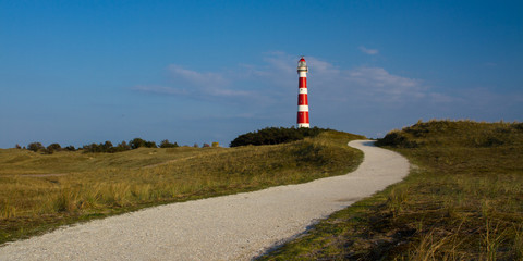 Path leading through the dunes towards vuurtoren, lighthouse of Ameland