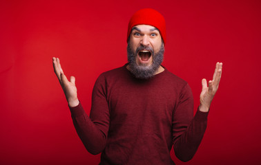 Photo of young man surprised looking at the camera over red background