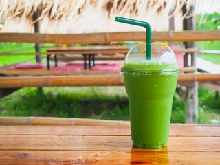Glass of green tea smoothie on wood table. nature background blurred