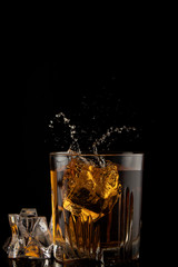 Glass of whiskey with splash on black background