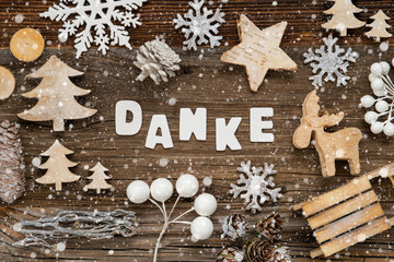 White Letters Building The Word Danke Means Thank You. Wooden Christmas Decoration Like Tree, Sled And Star. Brown Wooden Background With Snowflakes