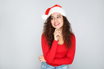 Beautiful american woman in santa hat on grey background
