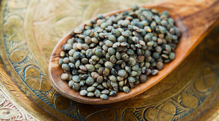 Puy Lentils -  French Green legume, dried grains on wooden spoon.