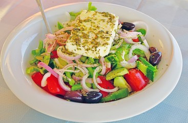 A Greek salad with a slice of feta cheese at a Greek tavern