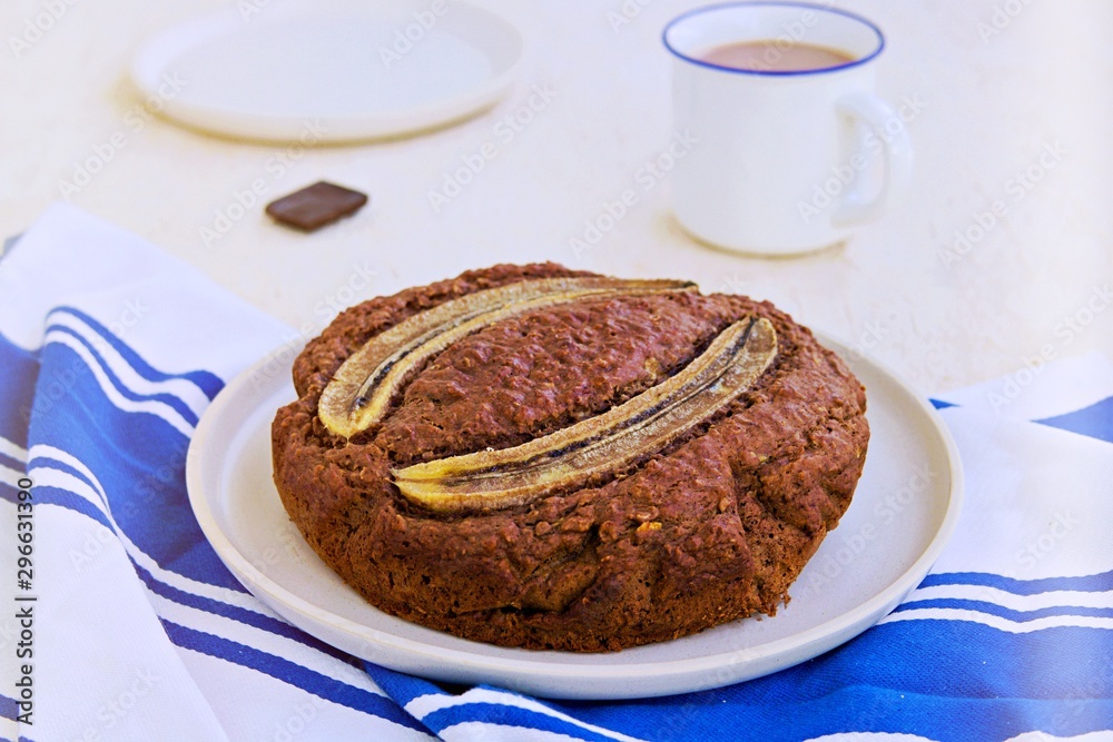 Canvas Prints Banana bread with oatmeal and cocoa on a white ceramic plate on a light concrete background. American cuisine. Baking with banana recipes.