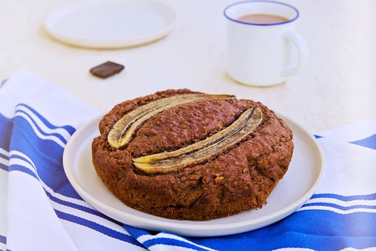 Banana bread with oatmeal and cocoa on a white ceramic plate on a light concrete background. American cuisine. Baking with banana recipes.