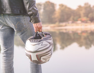 Man holds motorcycle helmet in front of the river.