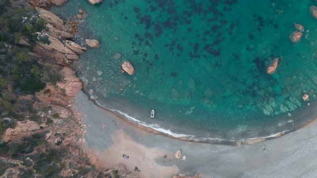 aerial 4k drone view of scenic amazing  beach cove, rocks cliff a boat and sandy beach - cala tinnari, costa paradiso - sardinia italy